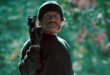 Robert Bronzi holding a gun in a jungle